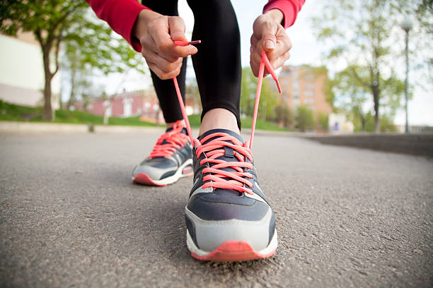 cordón manos de mujeres corriendo zapatos. primer plano - zapatillas de deporte fotografías e imágenes de stock