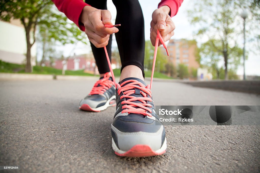 Female hands lacing running shoes. Closeup Sporty woman tying shoelace on running shoes before practice. Female athlete preparing for jogging outdoors. Runner getting ready for training. Sport active lifestyle concept. Close-up Walking Stock Photo