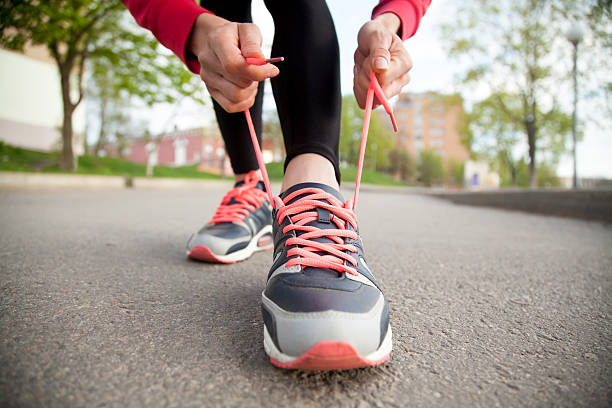 Female hands lacing running shoes. Closeup Sporty woman tying shoelace on running shoes before practice. Female athlete preparing for jogging outdoors. Runner getting ready for training. Sport active lifestyle concept. Close-up human leg photos stock pictures, royalty-free photos & images