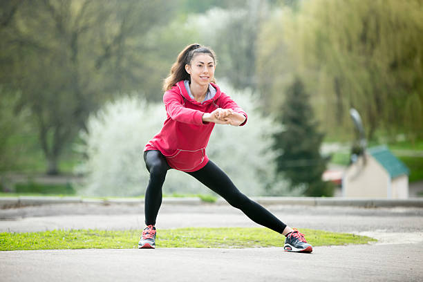 Runner woman doing side lunges before jogging Portrait of sporty woman doing stretching exercises in park before training. Female athlete preparing for jogging outdoors. Runner doing side lunges. Sport active lifestyle concept. Full length lunge stock pictures, royalty-free photos & images