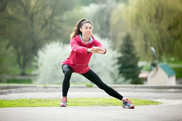 Photo of Runner woman doing side lunges before jogging