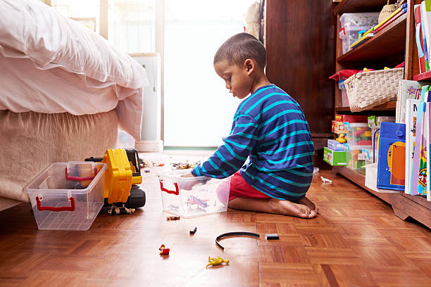 Playing and packing Shot of a young boy sitting on the floor with toys in a bedroom tidy room stock pictures, royalty-free photos & images