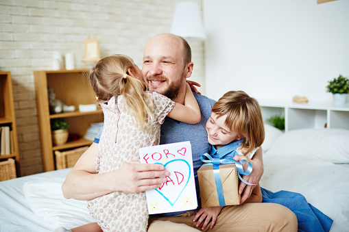 Little daughters embracing their father to congratulate with fathers day