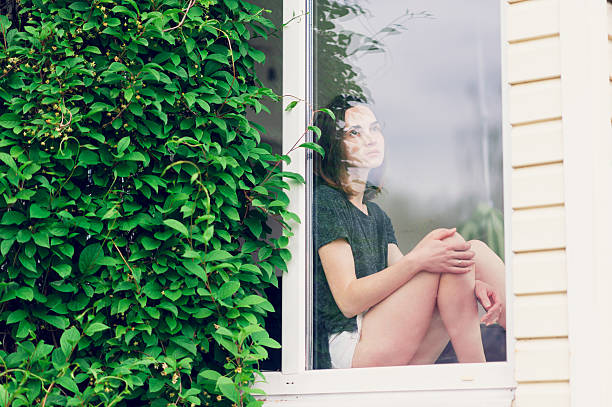 istock lonely girl sitting on the window 531921176