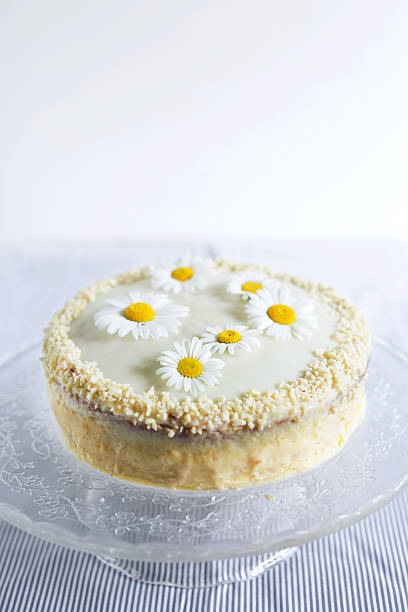 White chocolate cake with almonds decorated with flowers, white daisys and crumbs of almonds.