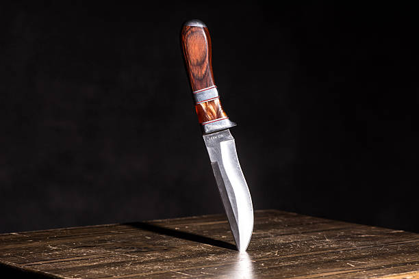 Knife stuck in a table on  black background