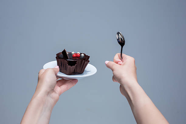 istock Female hands keeping cake with spoon on gray 531926038