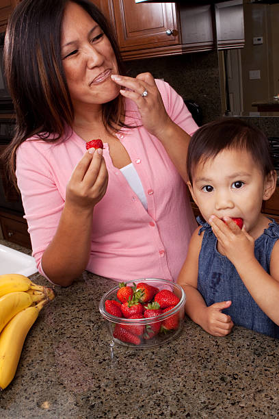 istock Mother and daughter eating strawberries in the kitchen 531927021