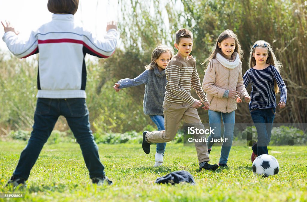 children running after ball children running after ball in spring park Active Lifestyle Stock Photo