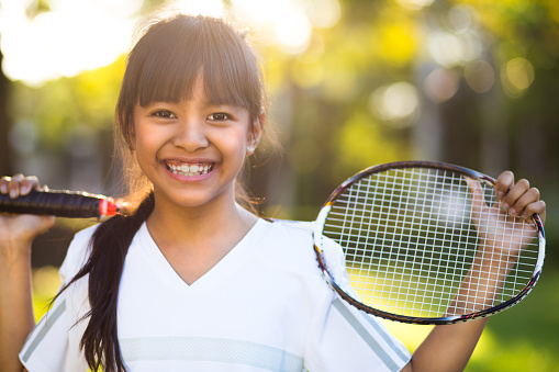 Closeup cute little asian girl holding a badminton racket, Outdoor