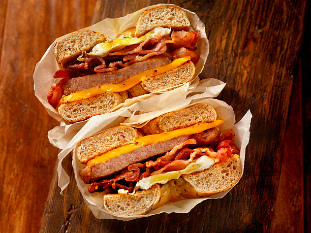 bagel, pancetta, salsicce e uova colazione sandwich - sandwich eggs bacon breakfast foto e immagini stock