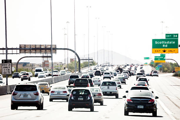 Suburban street scene: cars, motorcycle, pedestrian on busy two-lane road. Captures daily commute, traffic flow, suburban life, transportation challenges and road safety in residential areas.