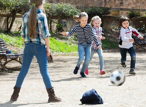 Young kids playing street football outdoors in spring day