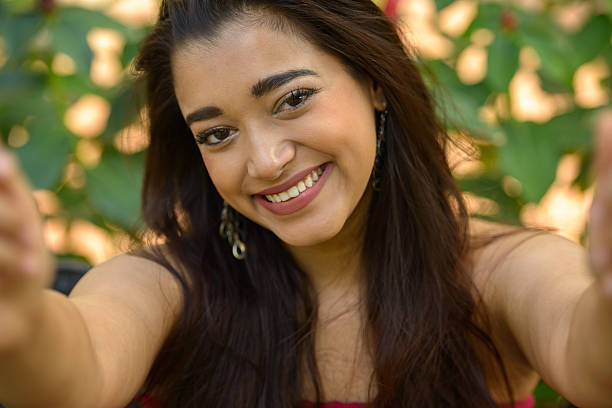 istock Indian woman sitting on park while taking selfie picture 531939024