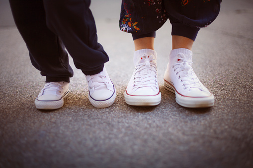 Close-up of mom and boy wearing sneakers in urban scene.