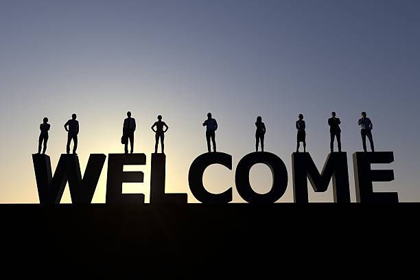 Welcome group of peole Group of people standing on the word welcome at sunset creating a silhouette. hello single word photos stock pictures, royalty-free photos & images