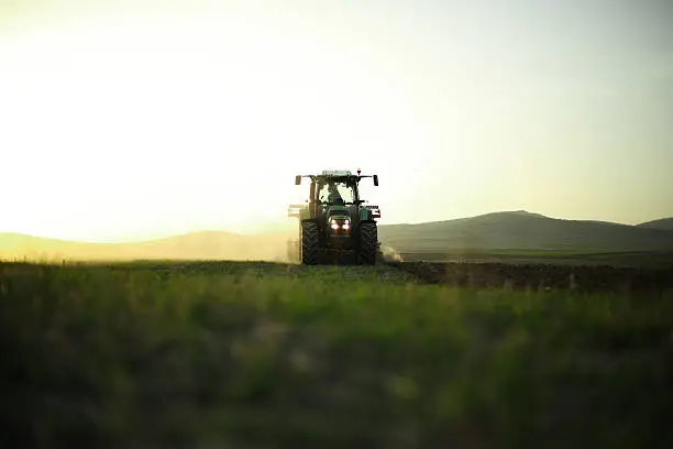 continuation of the work pace all day. sunset taken in backlight duration field tractor