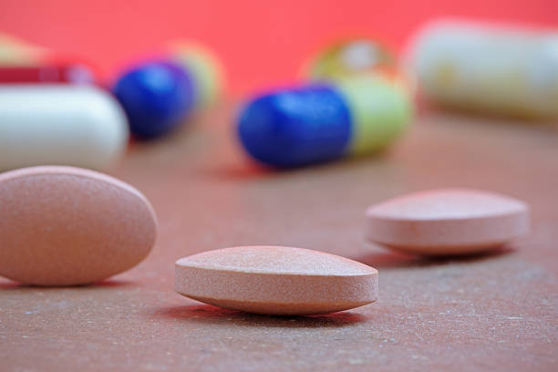 Statins in Close Up Close up of statin tablet or generic pill with out of focus tablets in background statin photos stock pictures, royalty-free photos & images