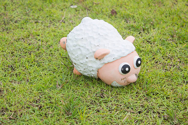 Cute cement sheep on green grass