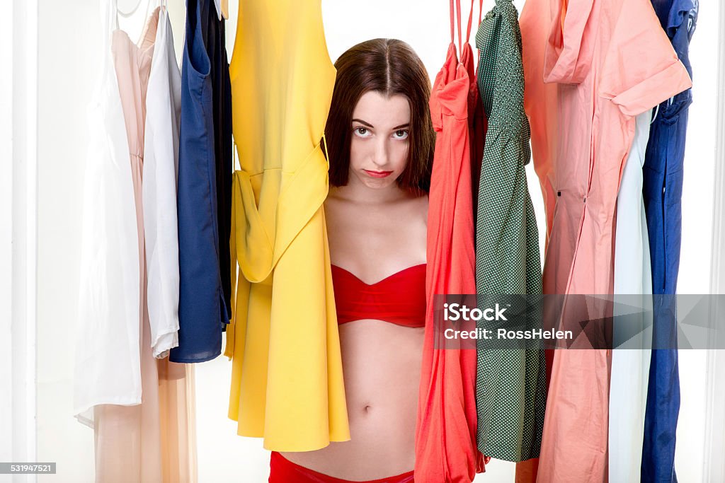 Woman in wardrobe Young sad woman in underwear thinking what dress to wear in the wardrobe. Nothing to wear concept 2015 Stock Photo