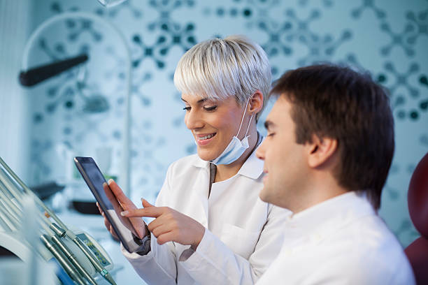 istock Dentist showing female patient x-rays on tablet 531948151