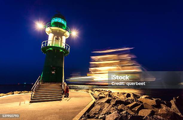 Lighthouse In Sunset With Large Sailing Ship Stock Photo - Download Image Now - 2015, Architecture, Baltic Sea