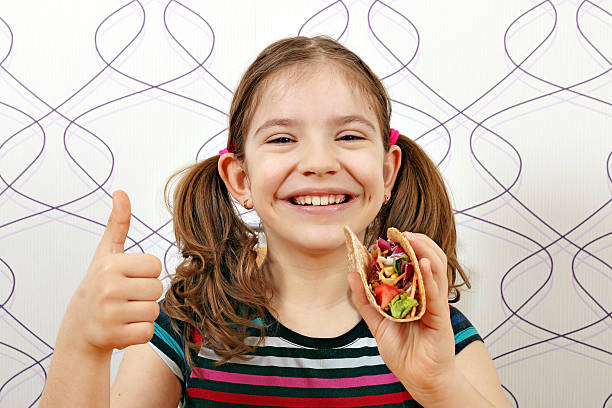 happy little girl with tacos and thumb up stock photo