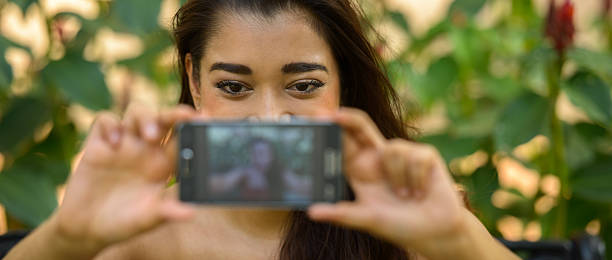 istock Indian woman sitting on park while taking selfie picture 531967212