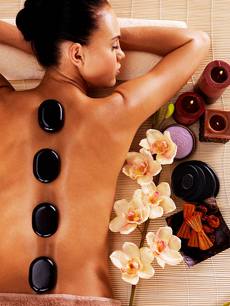 Adult woman relaxing in spa salon with hot stones on Adult woman relaxing in spa salon with hot stones on body. Beauty treatment therapy hot stone massage stock pictures, royalty-free photos & images