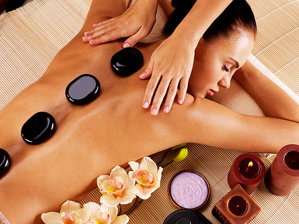 adult woman having hot stone massage in spa salon - alternatieve geneeskundige fotos stockfoto's en -beelden