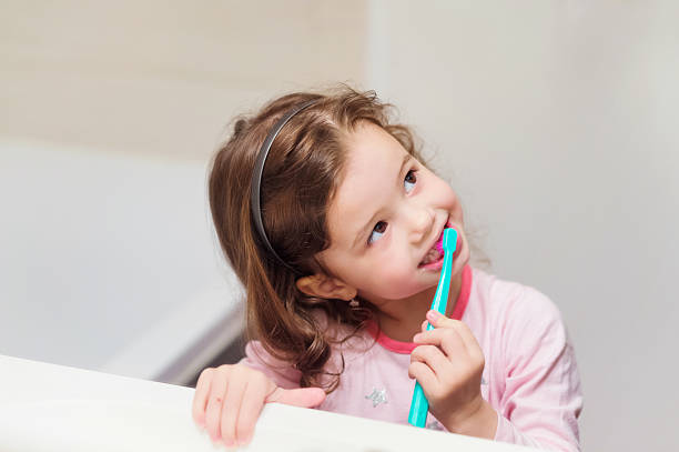 Little girl in pink pyjamas in bathroom brushing teeth Cute little girl in pink pyjamas in bathroom brushing her teeth brushing teeth stock pictures, royalty-free photos & images