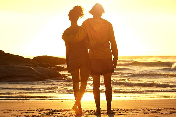 istock Man with arm around woman standing at the beach 531973774