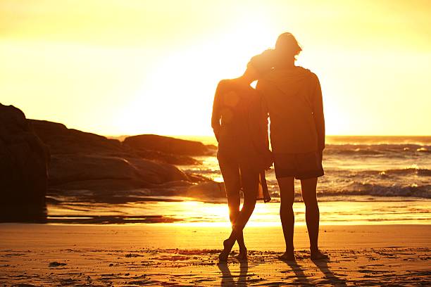 istock Loving couple standing by the beach looking at sunset 531974230