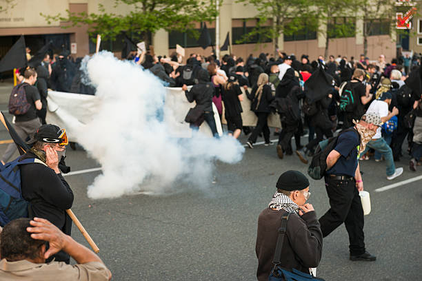 Seattle Protest Seattle, USA - May 1, 2016: Protestors run from flash bang grenades after clashing with police officers in the annual Anti-Capitalist Protest on 2nd avenue Late in the day. german social democratic party photos stock pictures, royalty-free photos & images