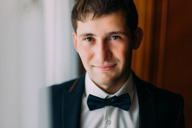 istock Handsome brunette man in blue bow tie posing near window 531980250