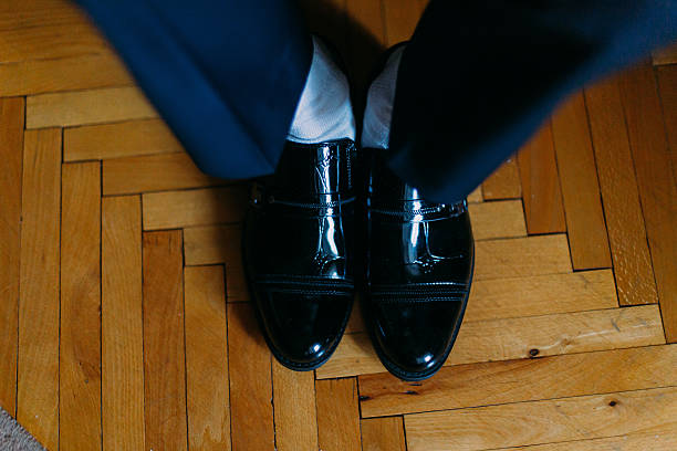 istock Handsome confident groom in blue suit putting on black shoes 531980314