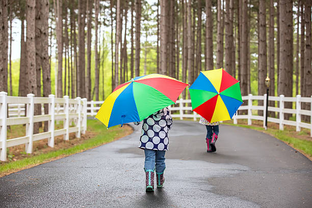istock Two Young Girls Walking Down Driveway With Umbrellas 531981776