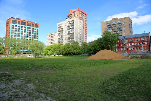 Big pile of sand on a wasteland near the apartment buildings