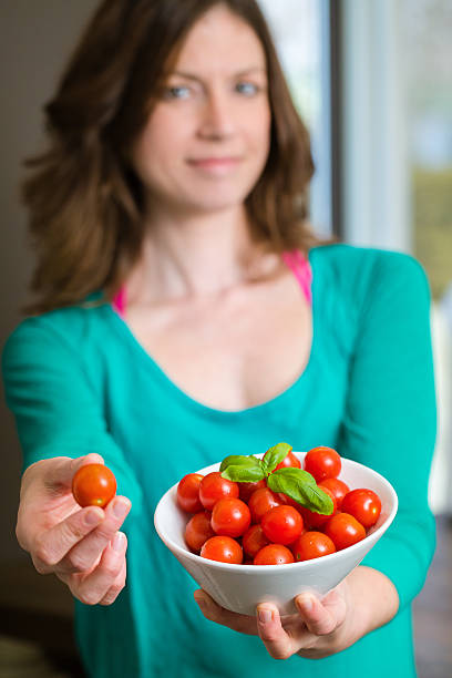 Young woman showing a cherry tomatoes
