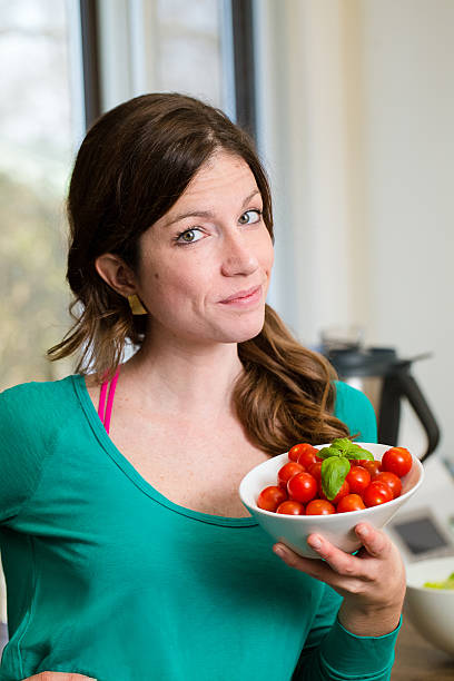 Young woman showing a cherry tomatoes bowl