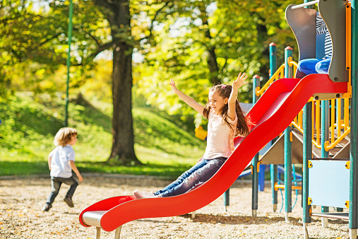 Kids jumping on inflatable trampoline, having fun visiting amusement park during a summer vacation. Brother with a sister spending leisure time together