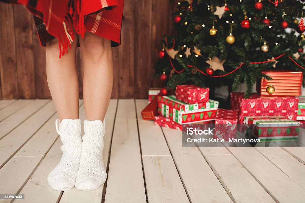 Woman standing in socks at decorated Christmas tree Beautiful woman legs in socks and decorated Christmas tree with gifts 2015 Stock Photo