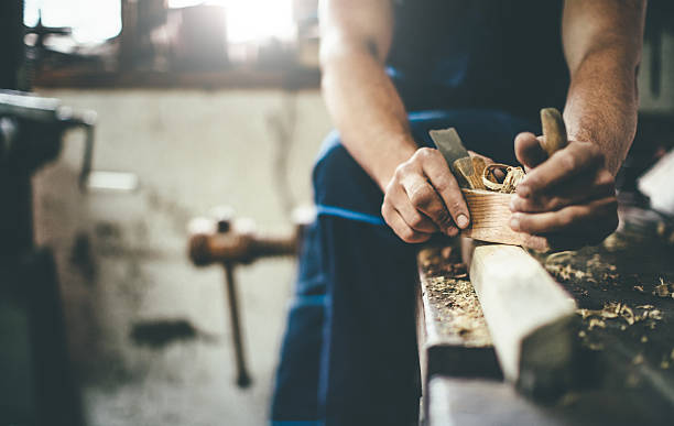 carpenter scraping wood with planer