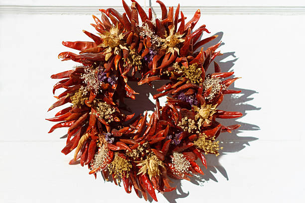 santa-fe-stil: red chili kranz auf weiß tür - wreath chili pepper pepper ristra stock-fotos und bilder