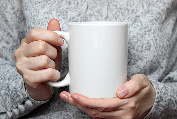 Girl is holding white cup in hands.