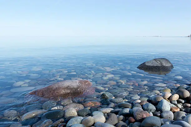 Ripples on the water surface in shallow water with colourful stones.