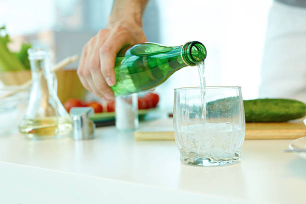 Mineral water in bottle Man pouring mineral water in glass tonic water stock pictures, royalty-free photos & images