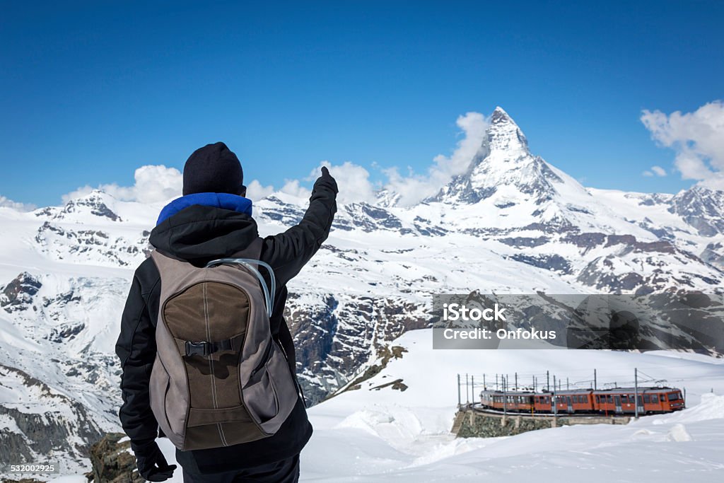 Woman Hiker with Backpack Poiting at Matterhorn Woman Hiker with Backpack Pointing at Matterhorn mountain summit in Switzerland on a nice sunny day with clear sky. Nature Stock Photo