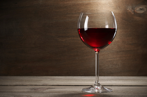 Glass of red wine on rustic wooden background with copy space.