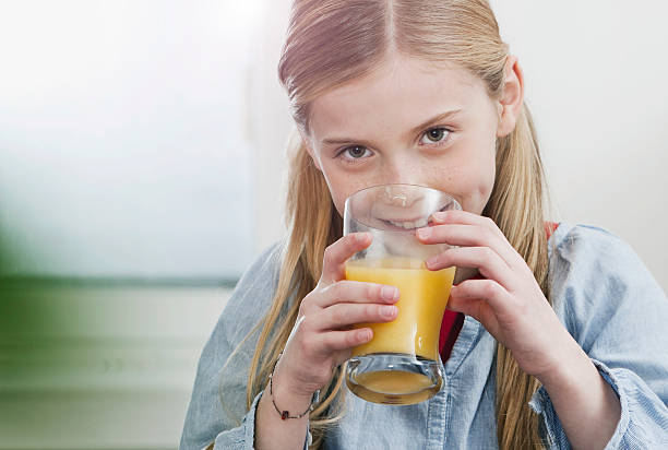 istock Blonde girl drinking orange juice smiling 532010219